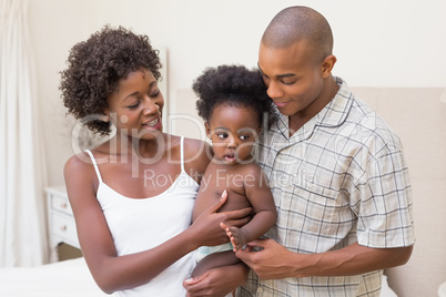 Happy couple on bed with baby daughter