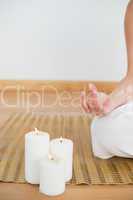 Woman sitting in lotus pose beside white candles