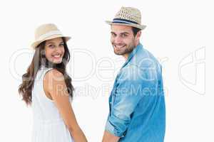 Happy hipster couple holding hands and smiling at camera