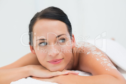 Peaceful brunette lying with salt scrub on back