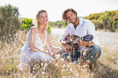 Handsome man serenading his girlfriend with guitar