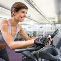 Fit smiling woman working out on the exercise bike