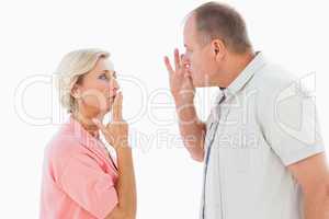 Older couple holding hands to mouth for silence