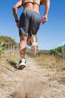 Shirtless man jogging with heart rate monitor around chest