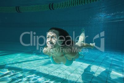 Pretty brunette smiling and swimming underwater