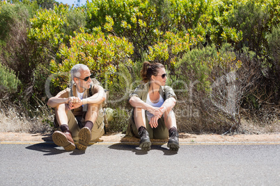 Hitch hiking couple sitting on the side of the road