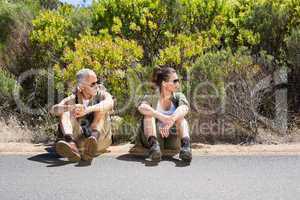 Hitch hiking couple sitting on the side of the road