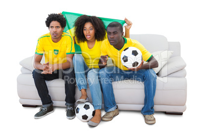 Brazilian football fans in yellow sitting on the sofa
