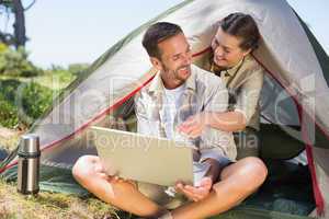Outdoorsy couple looking at the laptop outside tent