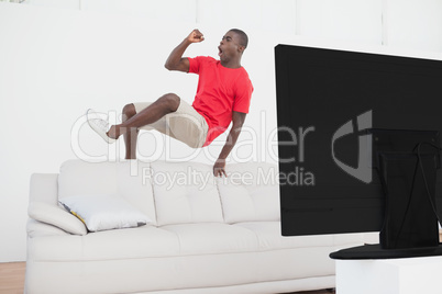 Football fan jumping over couch cheering