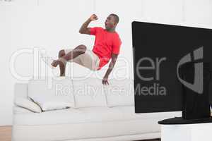 Football fan jumping over couch cheering