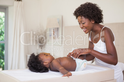 Happy mother with baby girl on changing table