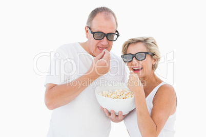 Mature couple wearing 3d glasses eating popcorn
