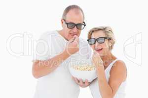 Mature couple wearing 3d glasses eating popcorn