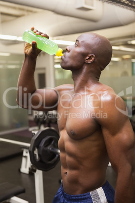 Muscular man drinking energy drink in gym