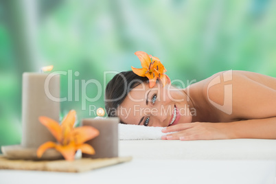 Beautiful brunette relaxing on massage table smiling at camera