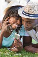 Happy young couple listening to music on the grass