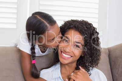 Pretty mother sitting on the couch with her daughter smiling at