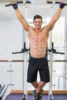 Shirtless male body builder doing pull ups