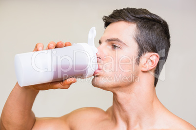 Close-up of a sporty young man drinking protein