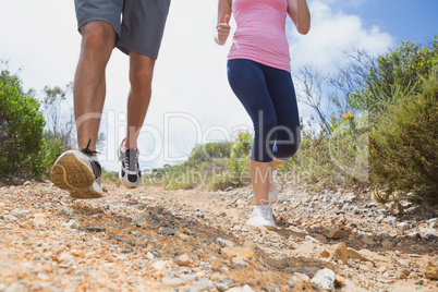 Fit couple running down mountain trail