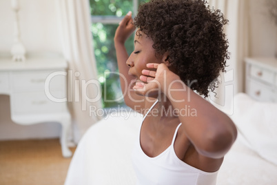 Pretty woman sitting on bed yawning