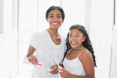 Pretty mother brushing her teeth with her daughter