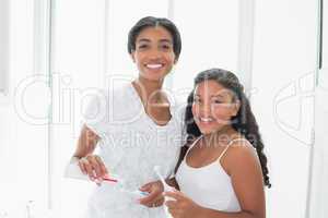 Pretty mother brushing her teeth with her daughter