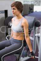 Healthy brunette using weights machine for arms