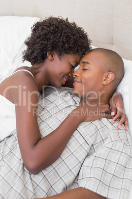 Intimate couple cuddling lying on their bed