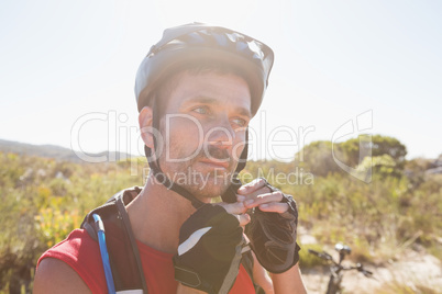 Fit cyclist adjusting helmet strap on country terrain