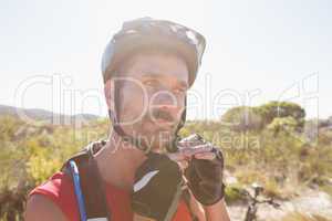 Fit cyclist adjusting helmet strap on country terrain