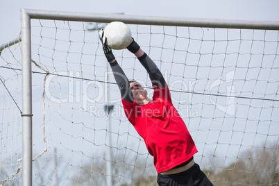 Goalkeeper in red jumping up to save a goal