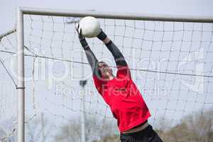 Goalkeeper in red jumping up to save a goal