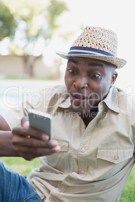 Smiling man relaxing in his garden texting on phone