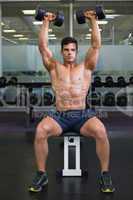 Muscular man exercising with dumbbells in gym