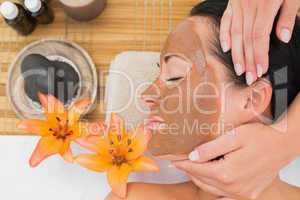 Peaceful brunette getting a mud treatment facial