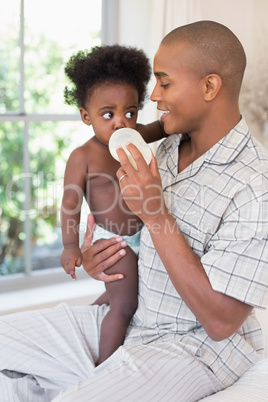 Happy father trying to feeding his baby girl