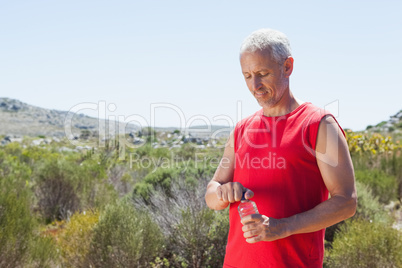 Fit man opening his water bottle on mountain trail