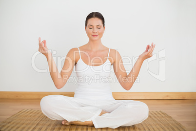 Smiling brunette sitting in lotus pose looking at camera