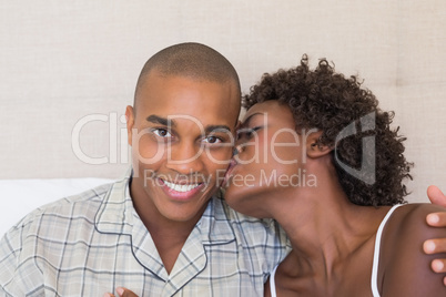 Happy couple sitting on bed cuddling