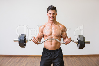 Shirtless muscular man lifting barbell in gym