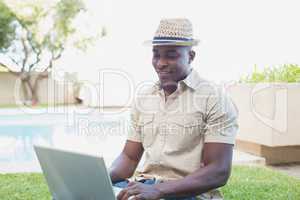 Handsome man relaxing in his garden using laptop