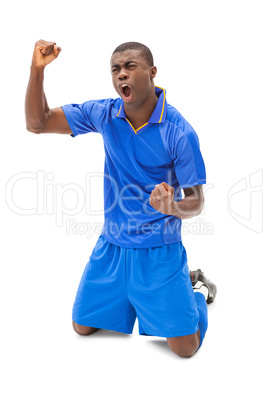 Excited football player in blue cheering on his knees