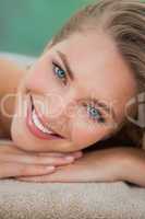 Peaceful blonde lying on towel smiling at camera