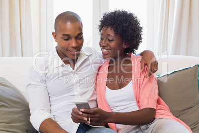 Cute couple relaxing on couch with smartphone Cute couple relaxing on couch with smartphone