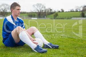 Football player in blue taking a break on the pitch