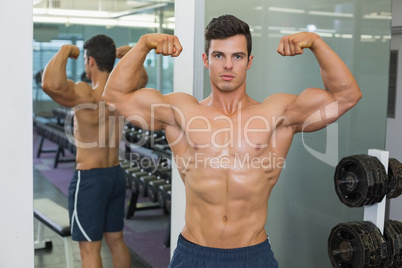 Shirtless muscular man flexing muscles in gym