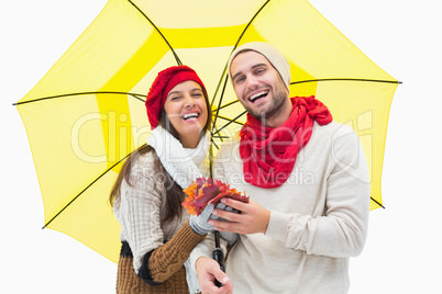 Attractive young couple in warm clothes holding umbrella and lea