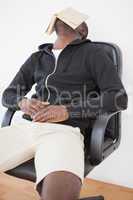 Casual man sitting on swivel chair with book over face
